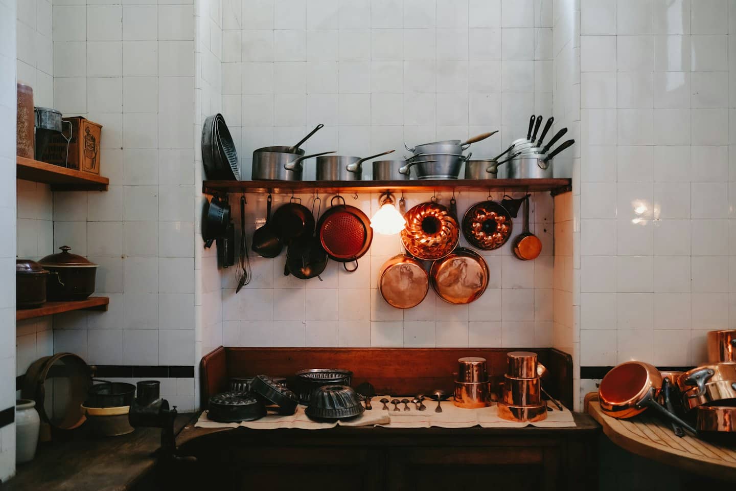 Copper pots and kitchen tools organized on wooden shelves.