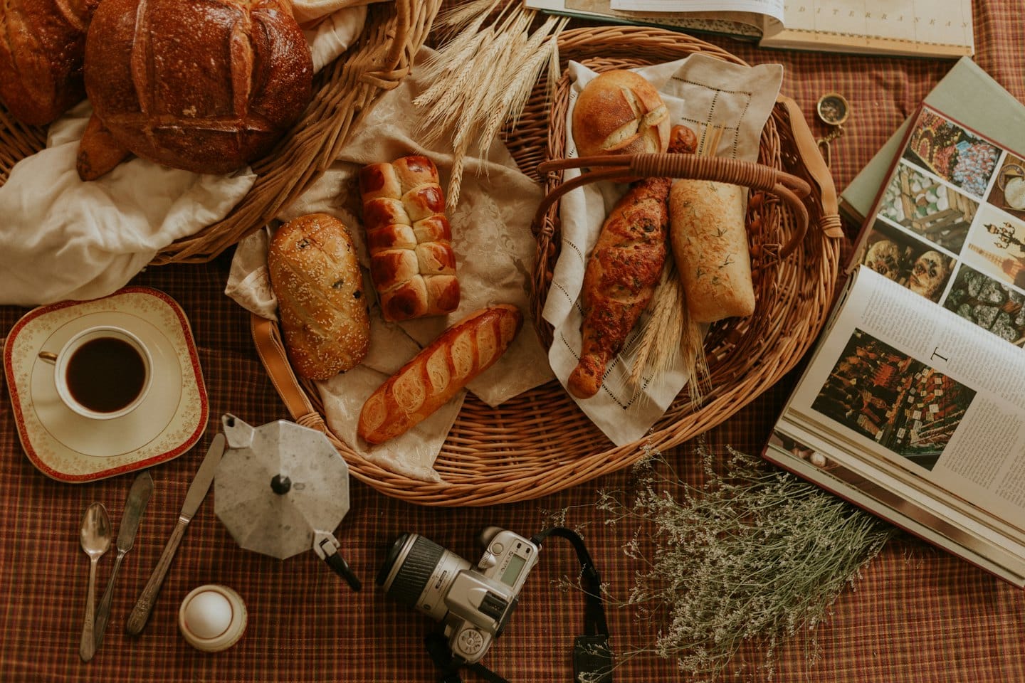 Freshly baked breads and coffee on a checkered blanket.