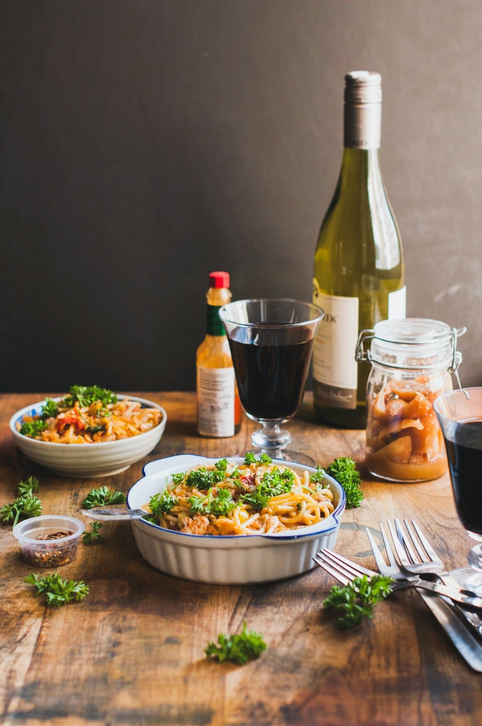 Two bowls of pasta with wine and pickled vegetables on a table.