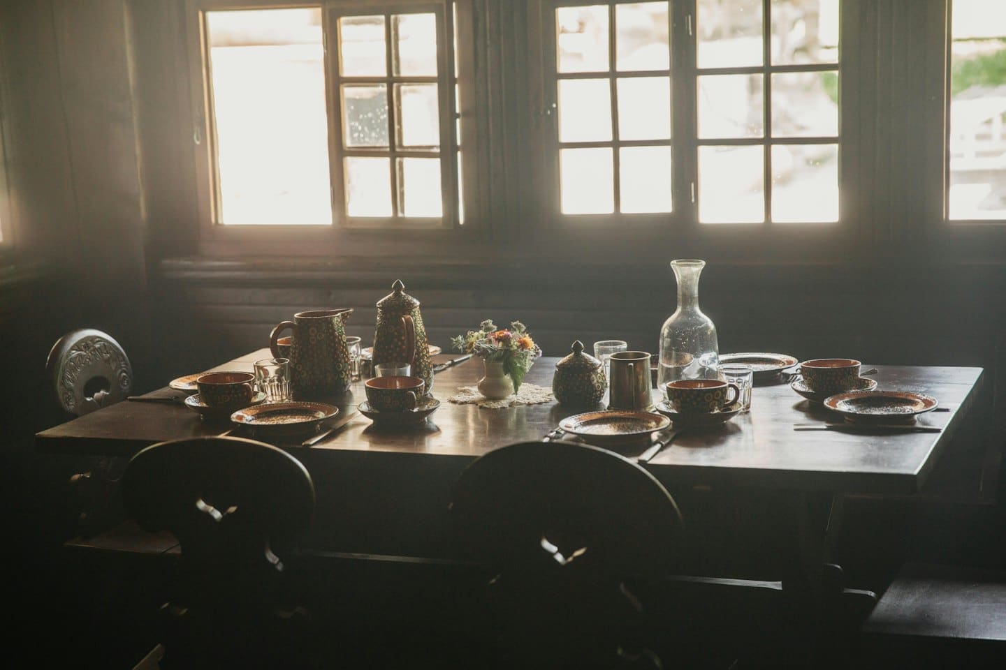 Wooden table set with dishes and wildflowers.