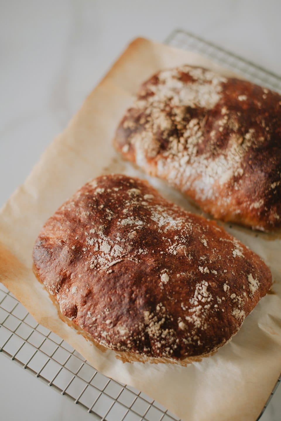 Two artisan sourdough loaves cooling on a wire rack.